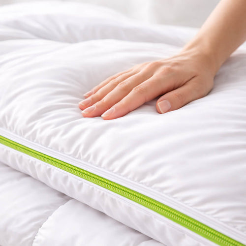 Hand touching a white duvet protector with a dust mite proof green zipper, on a white background