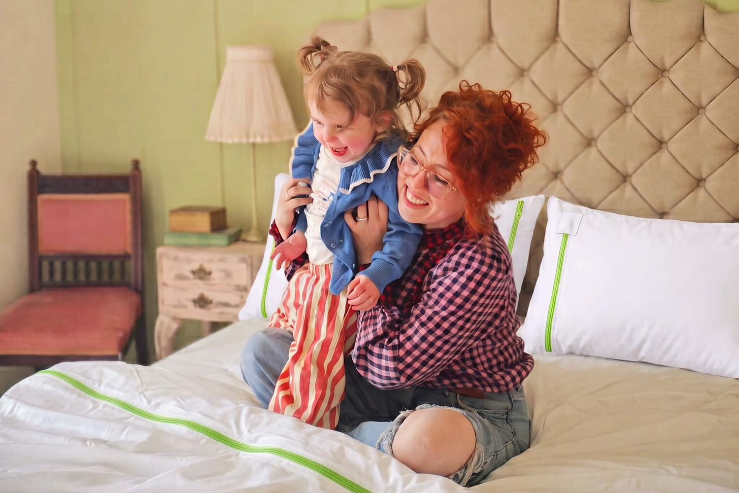 Smiling mum and young daughter playing on a bed fitted with iDustMite zipped dust mite protectors on the mattress, duvet and pillows